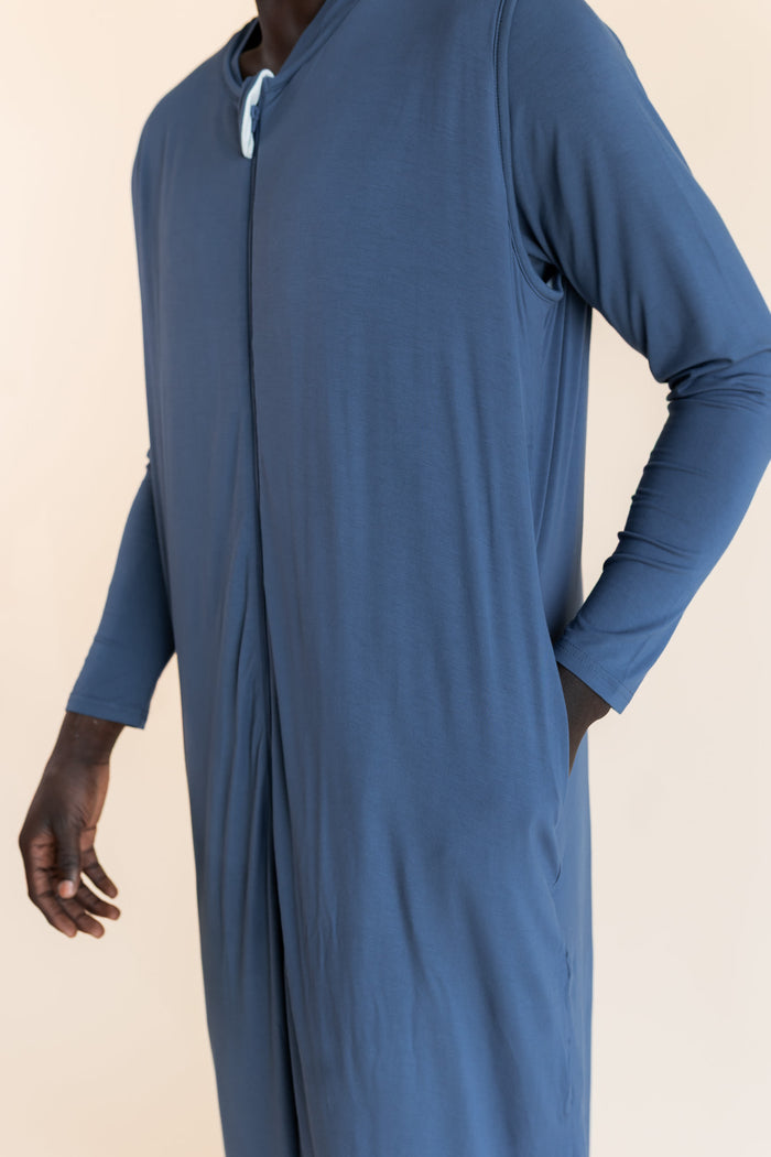 A man wearing a blue sleep sack with a split neckline and front opening, shown against a plain beige studio background.