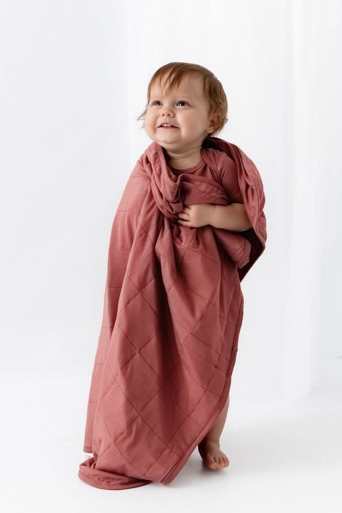 Baby wrapped in Baby Blanket in Ember on a white background