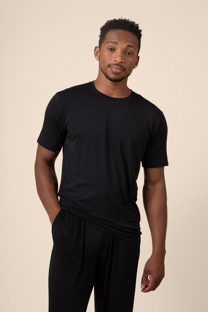 Man wearing a black t-shirt and pants on a beige background