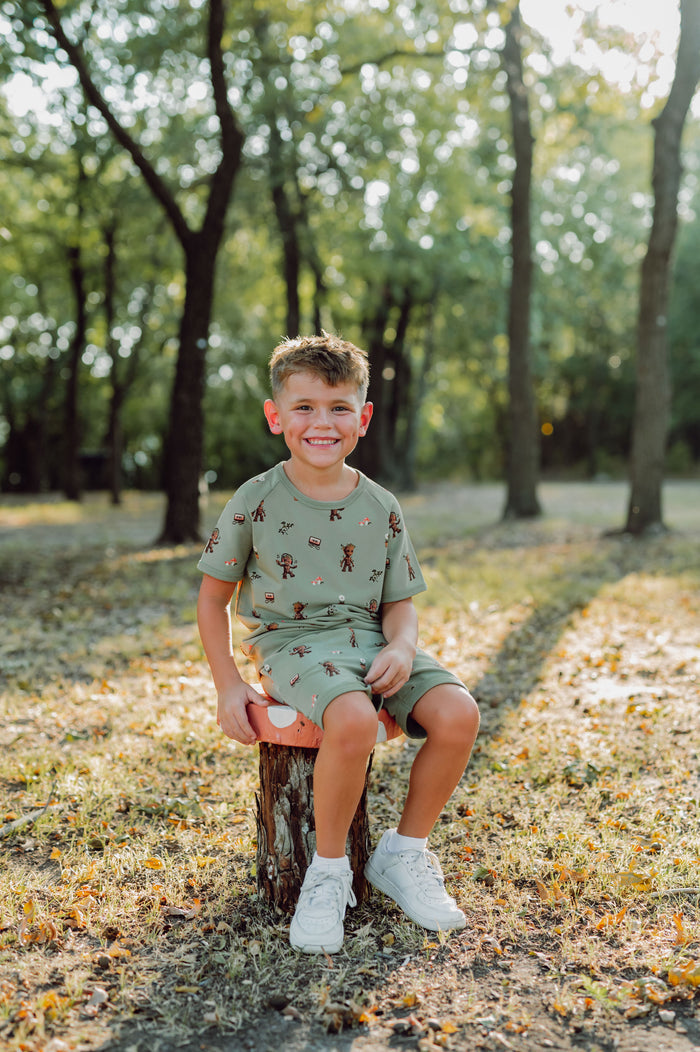 Boy outside sitting on a tree stump in groot short sleeve jogger set.