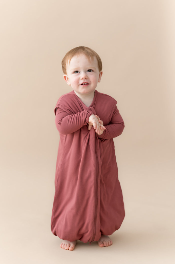 Child wearing Sleep Bag Walker in Ember 1.0 on a beige background