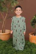 Boy smiling in Green Sleep Bag Walker in Groot 1.0 print standing between green plant pots and grass